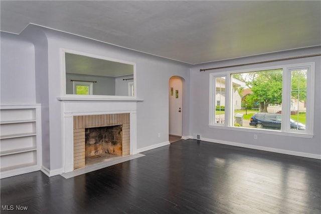 459 N Osborn Ave, Youngstown, OH 44509 - unfurnished living room with arched walkways, wood finished floors, a brick fireplace, and baseboards