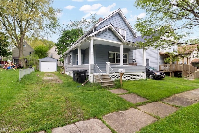 114 Mendel Ct, Elyria, OH 44035 - shotgun-style home featuring a porch, an outbuilding, a front lawn, and a garage