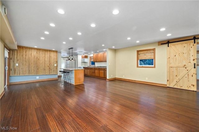 1287 E Garnet Ave, Port Clinton, OH 43452 - unfurnished living room featuring a barn door, dark wood-style floors, baseboards, and recessed lighting