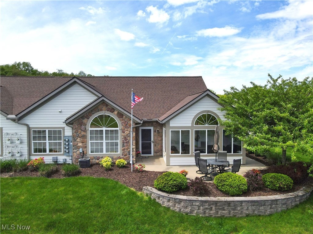 683 Crossings Cir, Tallmadge, OH 44278 - back of house featuring stone siding, a patio area, a yard, and central AC