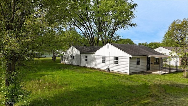 back of house featuring a yard and a shingled roof