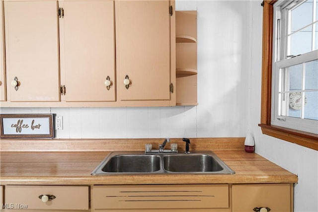 kitchen featuring a sink, light countertops, open shelves, and plenty of natural light