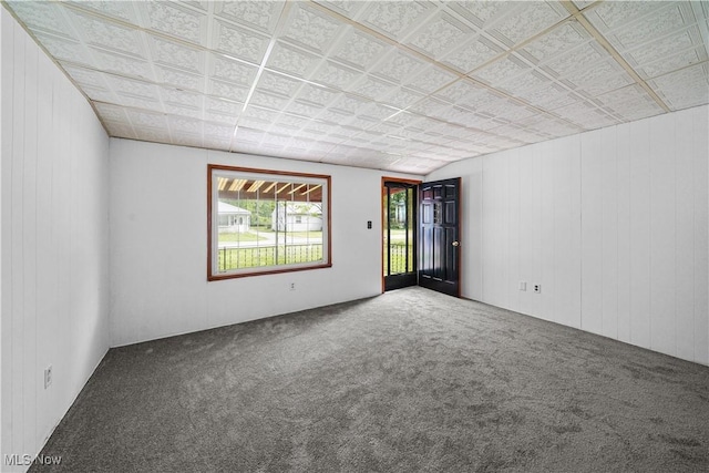spare room featuring carpet flooring, wood walls, and an ornate ceiling