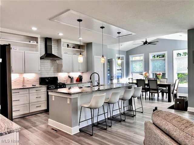 341 Cherry Rdg, Tallmadge, OH 44278 - kitchen featuring wall chimney exhaust hood, stainless steel gas range oven, a kitchen bar, light wood finished floors, and decorative backsplash