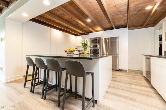 675 Wheatfield Dr, Aurora, OH 44202 - kitchen featuring appliances with stainless steel finishes, wooden ceiling, dark countertops, a breakfast bar area, and beamed ceiling