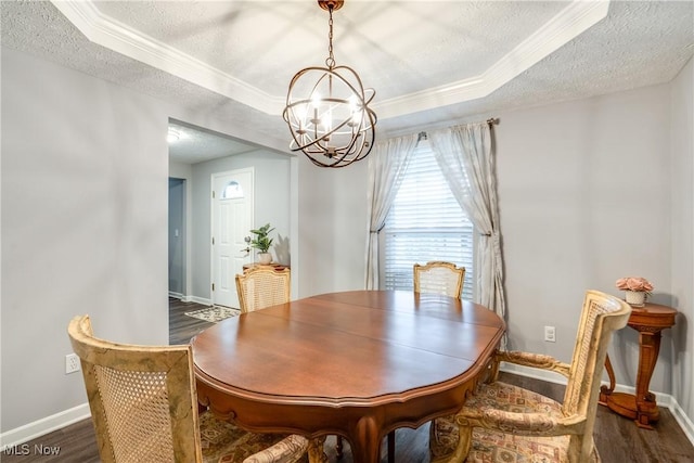dining room featuring a chandelier, a textured ceiling, a tray ceiling, crown molding, and dark wood-type flooring
