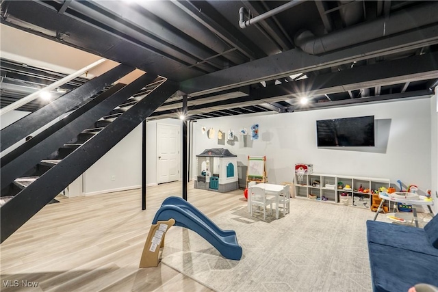 finished below grade area featuring wood finished floors and stairway