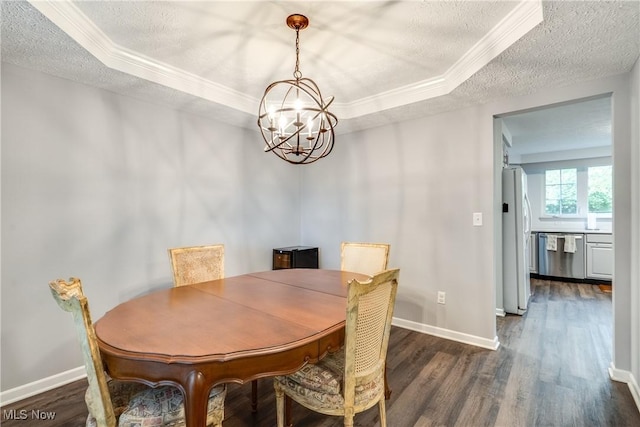 dining area with a textured ceiling, a chandelier, a tray ceiling, dark wood-style floors, and ornamental molding