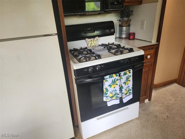 kitchen featuring gas stove, freestanding refrigerator, and black microwave