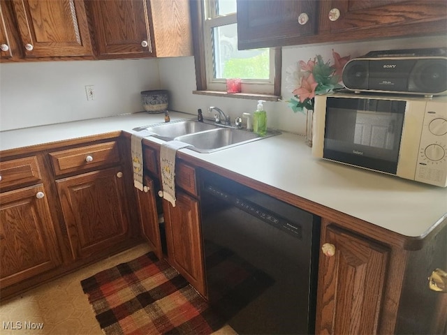 kitchen featuring dishwashing machine, a sink, light countertops, and brown cabinets