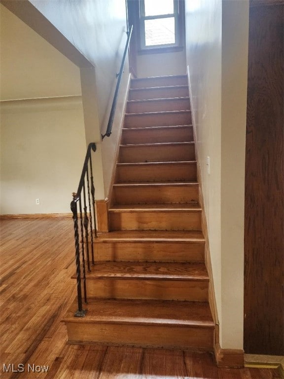staircase with wood finished floors and baseboards