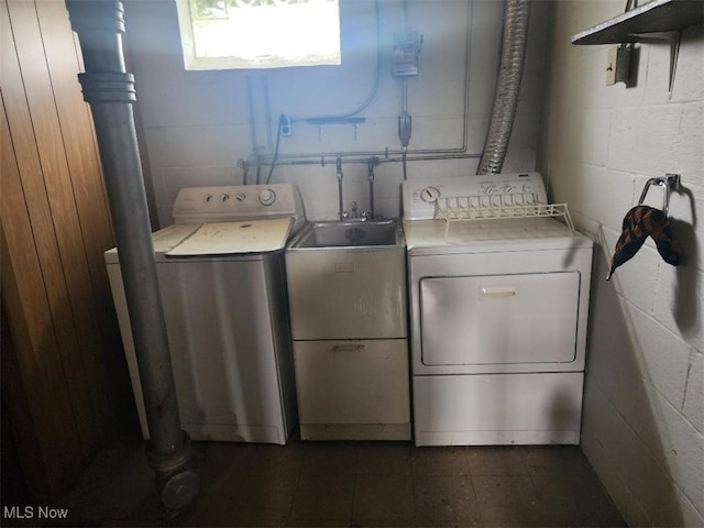 clothes washing area featuring washing machine and dryer and concrete block wall