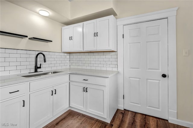kitchen with a sink, white cabinets, backsplash, and dark wood-style floors