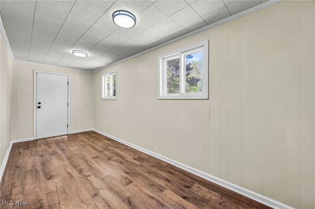 unfurnished room with wood finished floors, crown molding, and baseboards