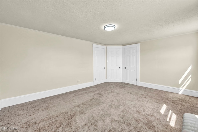 spare room with carpet floors, baseboards, a textured ceiling, and ornamental molding