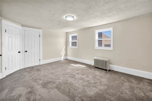 unfurnished bedroom featuring radiator heating unit, carpet flooring, baseboards, and a textured ceiling