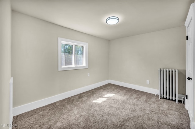 carpeted empty room featuring radiator and baseboards
