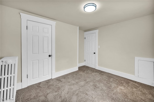 unfurnished bedroom with radiator, carpet, and baseboards