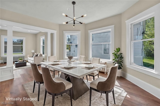 dining area featuring dark wood-type flooring, a chandelier, baseboards, and radiator