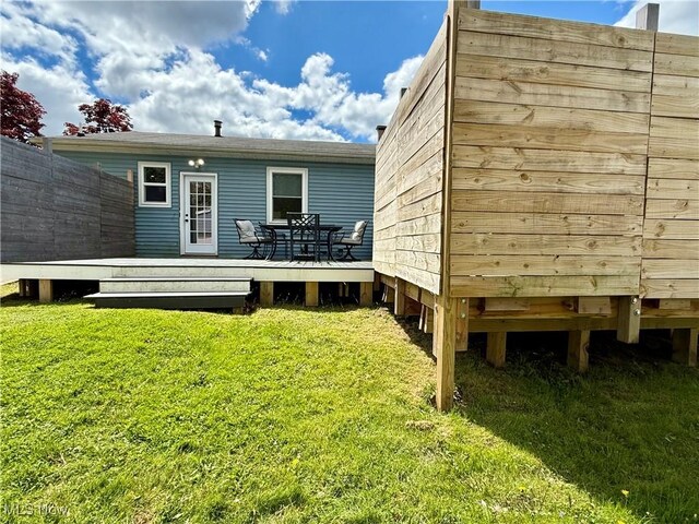 back of property featuring a wooden deck and a lawn