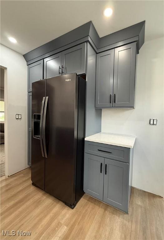 kitchen featuring stainless steel fridge, gray cabinets, light wood-style flooring, and light countertops