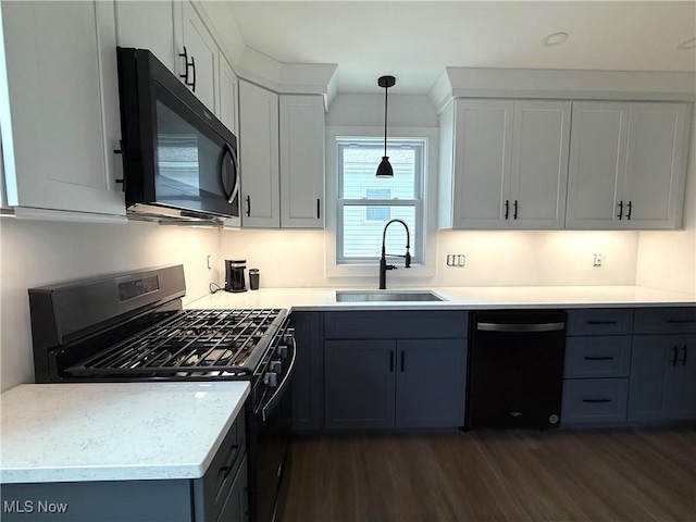 kitchen featuring stainless steel gas range oven, dishwasher, black microwave, a sink, and dark wood-style floors