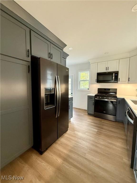 kitchen with appliances with stainless steel finishes, light countertops, light wood finished floors, recessed lighting, and white cabinets