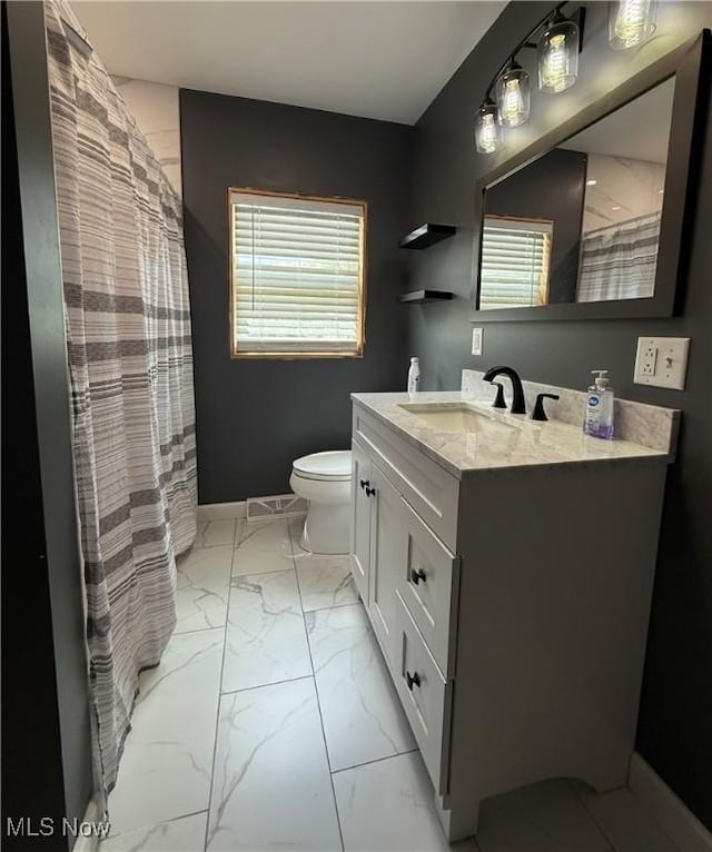 full bath with marble look tiles, toilet, vanity, and baseboards