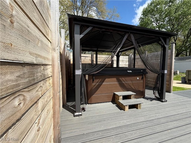 wooden terrace featuring a hot tub and a gazebo