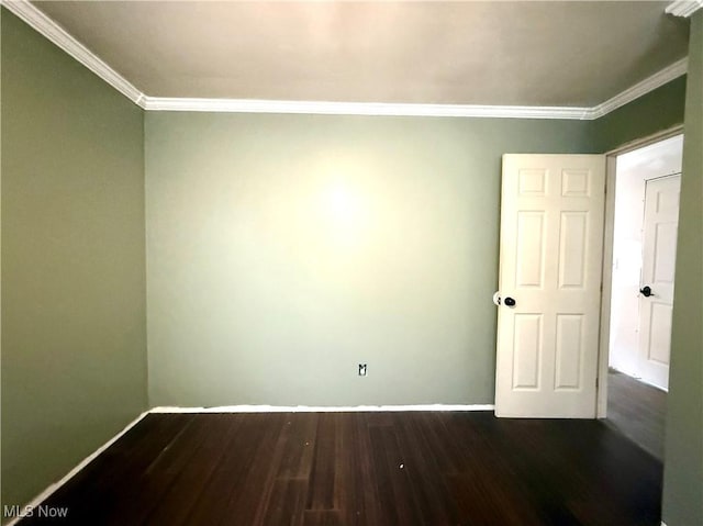 spare room featuring crown molding, dark wood-style flooring, and baseboards