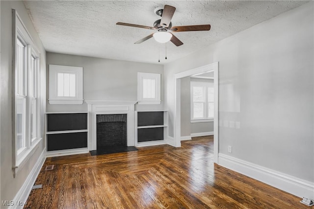 406 39th St, Vienna, WV 26105 - unfurnished living room with a textured ceiling, baseboards, ceiling fan, a fireplace with flush hearth, and plenty of natural light