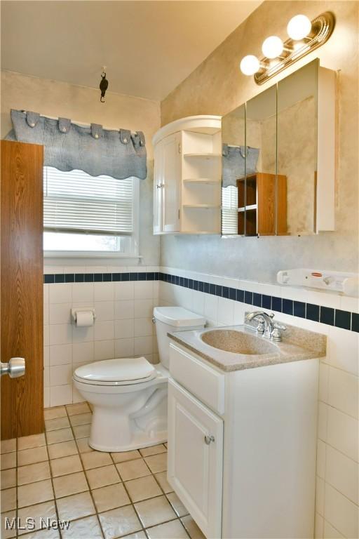 9960 Ridge Rdg, Farmdale, OH 44417 - half bathroom featuring toilet, tile patterned floors, tile walls, and vanity