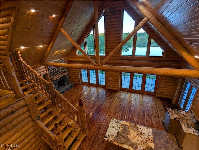 unfurnished living room featuring high vaulted ceiling, wood ceiling, log walls, hardwood / wood-style flooring, and a fireplace