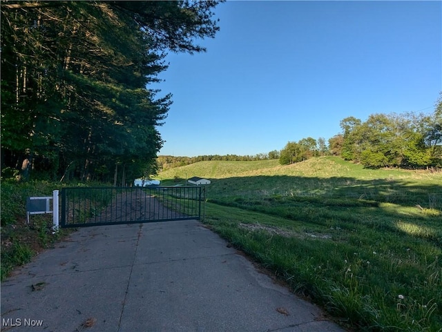 view of concrete surface featuring a gate, a rural view, and a gated entry