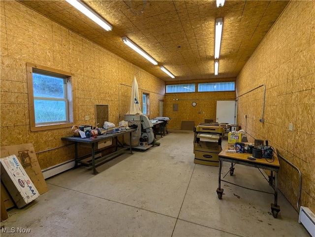 misc room with a baseboard heating unit, concrete flooring, and plenty of natural light