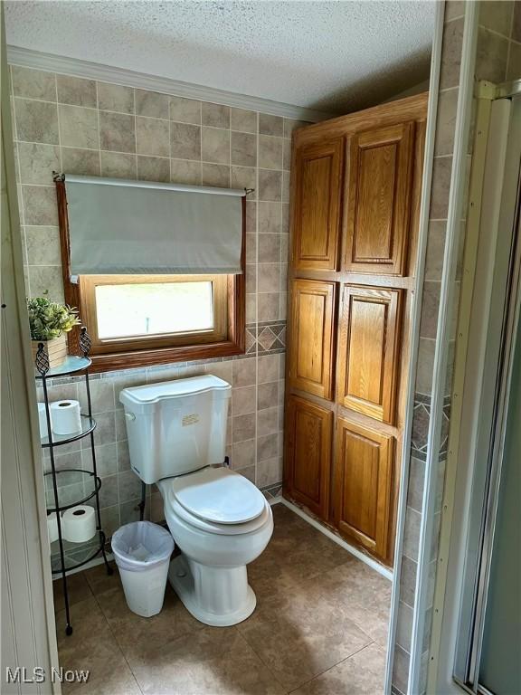 1367 Arner Rd, Chester, WV 26034 - bathroom with a textured ceiling, toilet, tile walls, tile patterned floors, and crown molding