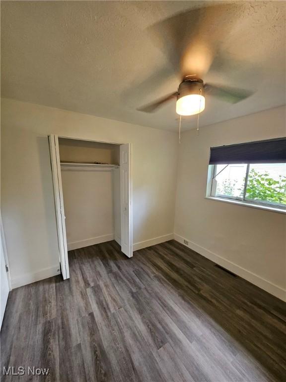 5897 Kimberly Dr, Bedford Heights, OH 44146 - unfurnished bedroom featuring dark wood-type flooring, a closet, a textured ceiling, and ceiling fan