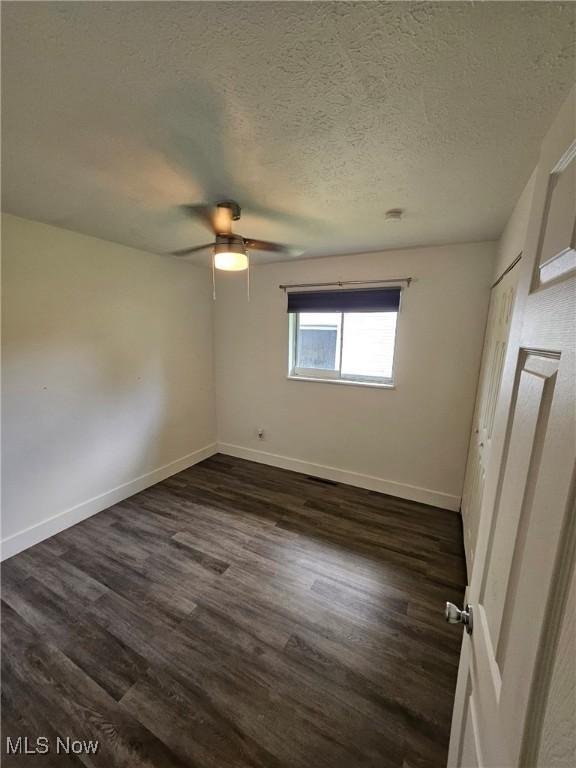 5897 Kimberly Dr, Bedford Heights, OH 44146 - unfurnished bedroom featuring dark wood finished floors, a textured ceiling, and a ceiling fan