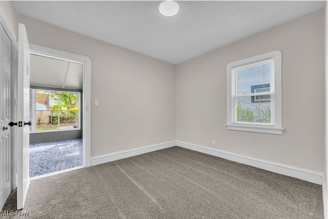unfurnished room with dark carpet and baseboards