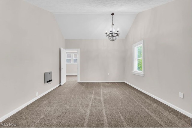 empty room featuring a chandelier, baseboards, carpet floors, heating unit, and high vaulted ceiling