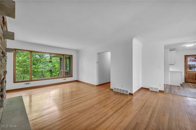 4422 Forest Hills Blvd, Parma, OH 44134 - unfurnished living room with arched walkways, light wood finished floors, baseboards, and a stone fireplace