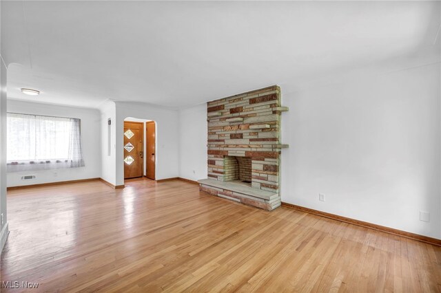 4422 Forest Hills Blvd, Parma, OH 44134 - unfurnished living room featuring light wood-type flooring, a stone fireplace, and baseboards