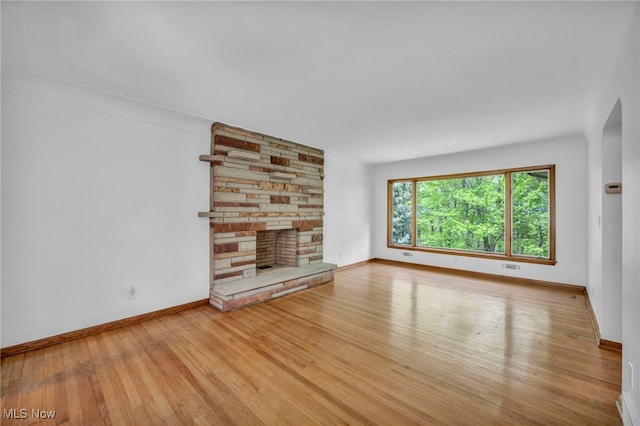 4422 Forest Hills Blvd, Parma, OH 44134 - unfurnished living room featuring a stone fireplace, wood finished floors, and baseboards