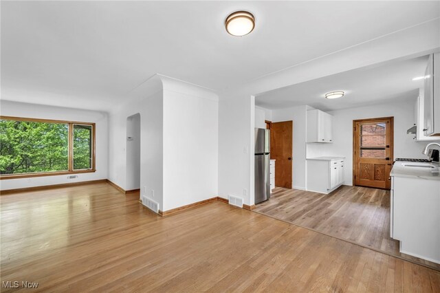4422 Forest Hills Blvd, Parma, OH 44134 - unfurnished living room featuring light wood-style flooring, baseboards, a sink, and arched walkways