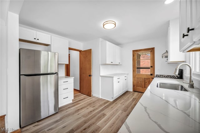 4422 Forest Hills Blvd, Parma, OH 44134 - kitchen with freestanding refrigerator, a sink, light wood-style floors, light stone countertops, and white cabinetry