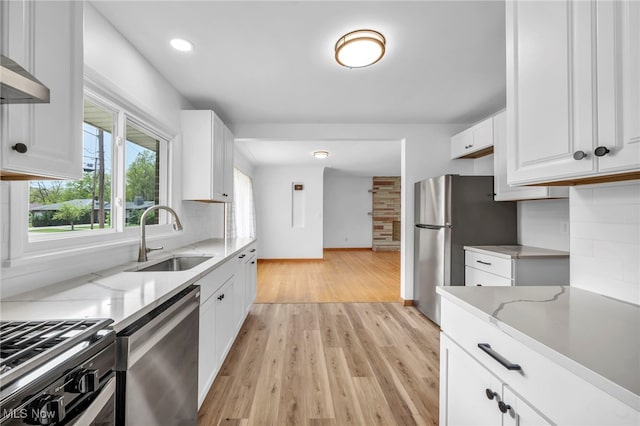 4422 Forest Hills Blvd, Parma, OH 44134 - kitchen with stainless steel appliances, a sink, white cabinets, light stone counters, and light wood finished floors