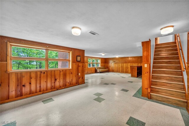 4422 Forest Hills Blvd, Parma, OH 44134 - unfurnished living room with wood walls, tile patterned floors, stairs, and baseboards