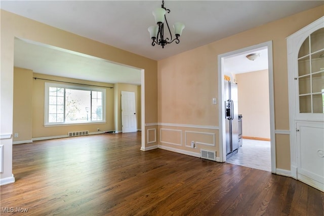 unfurnished room featuring wood finished floors, a chandelier, and wainscoting