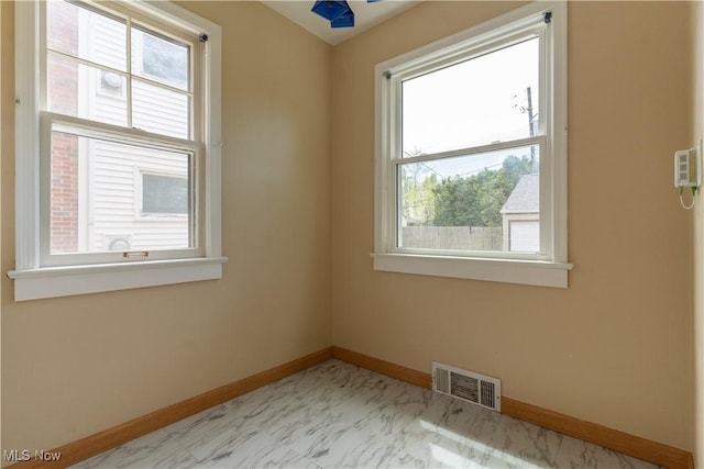 unfurnished room with baseboards and marble finish floors