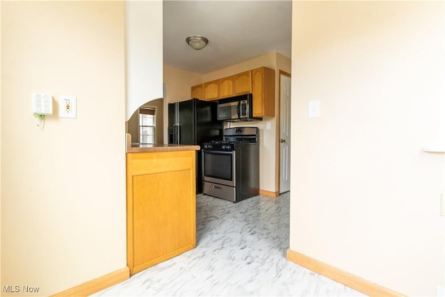 kitchen with black appliances, light marble finish floors, baseboards, and arched walkways
